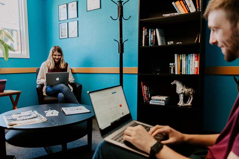 Two coworkers work on their laptops