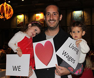 father and kids holding up we love living wages signs